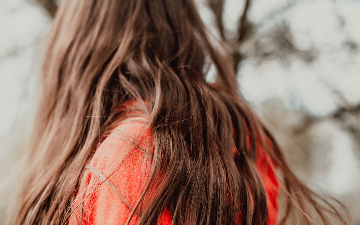 A close-up of a woman with long, flowing brown hair. Blurred background adds depth.