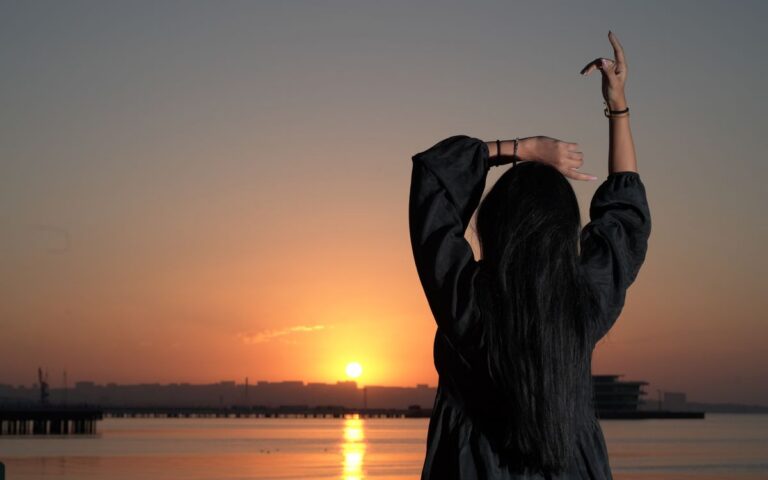 Serene sunset view in Baku with a woman gracefully posing by the water.