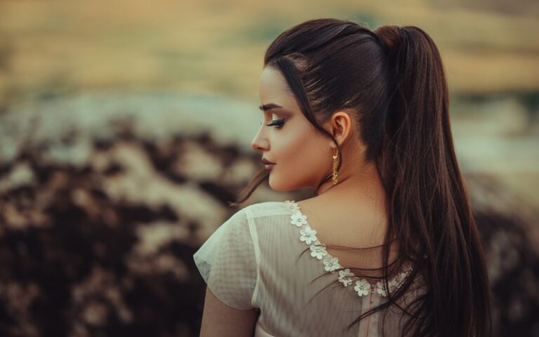A stylish woman with long brown hair wearing a white dress, shot from behind outdoors in Moscow, Russia.
