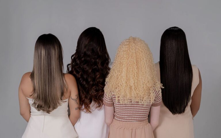 Four women showing diverse hairstyles from behind, emphasizing hair texture and color.