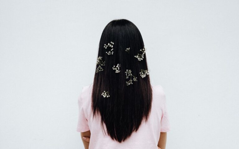 Elegant back view of a woman with long hair adorned with baby's breath on a white background
