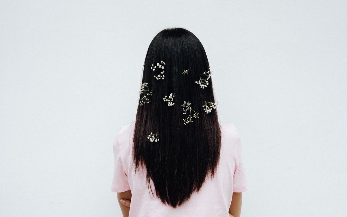 Elegant back view of a woman with long hair adorned with baby's breath on a white background