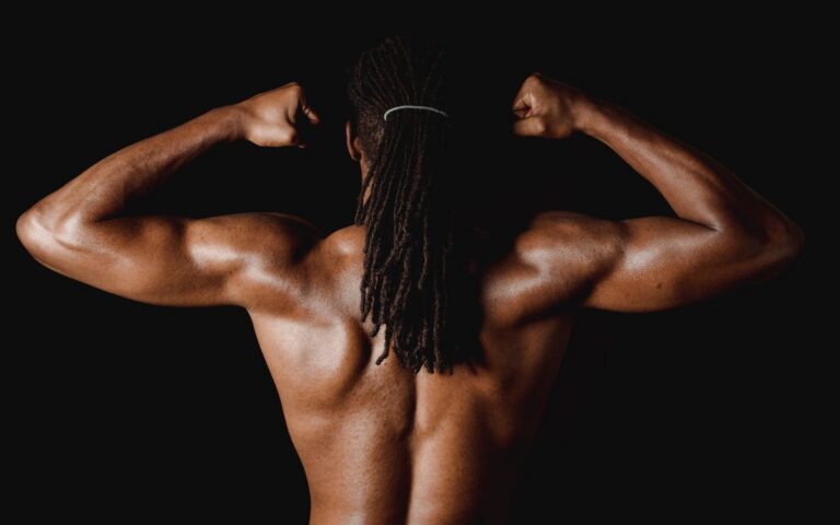 A strong man showcasing back muscle definition in a studio environment.